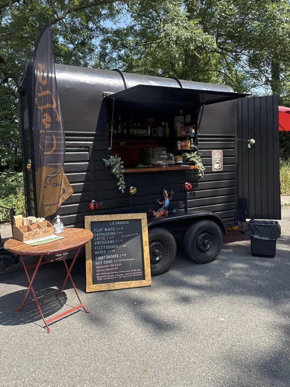 Leonard's Coffee trailer parked among trees on a sunny trading day